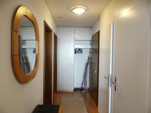 Ein Korridor mit einem spiegelnden Holzrahmen, einer weißen Tür und einem weißen Kleiderschrank mit Spiegel.