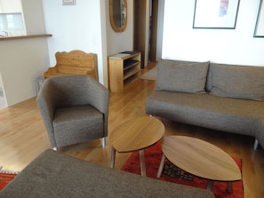 Un salon avec un canapé, un fauteuil et une petite table en bois.