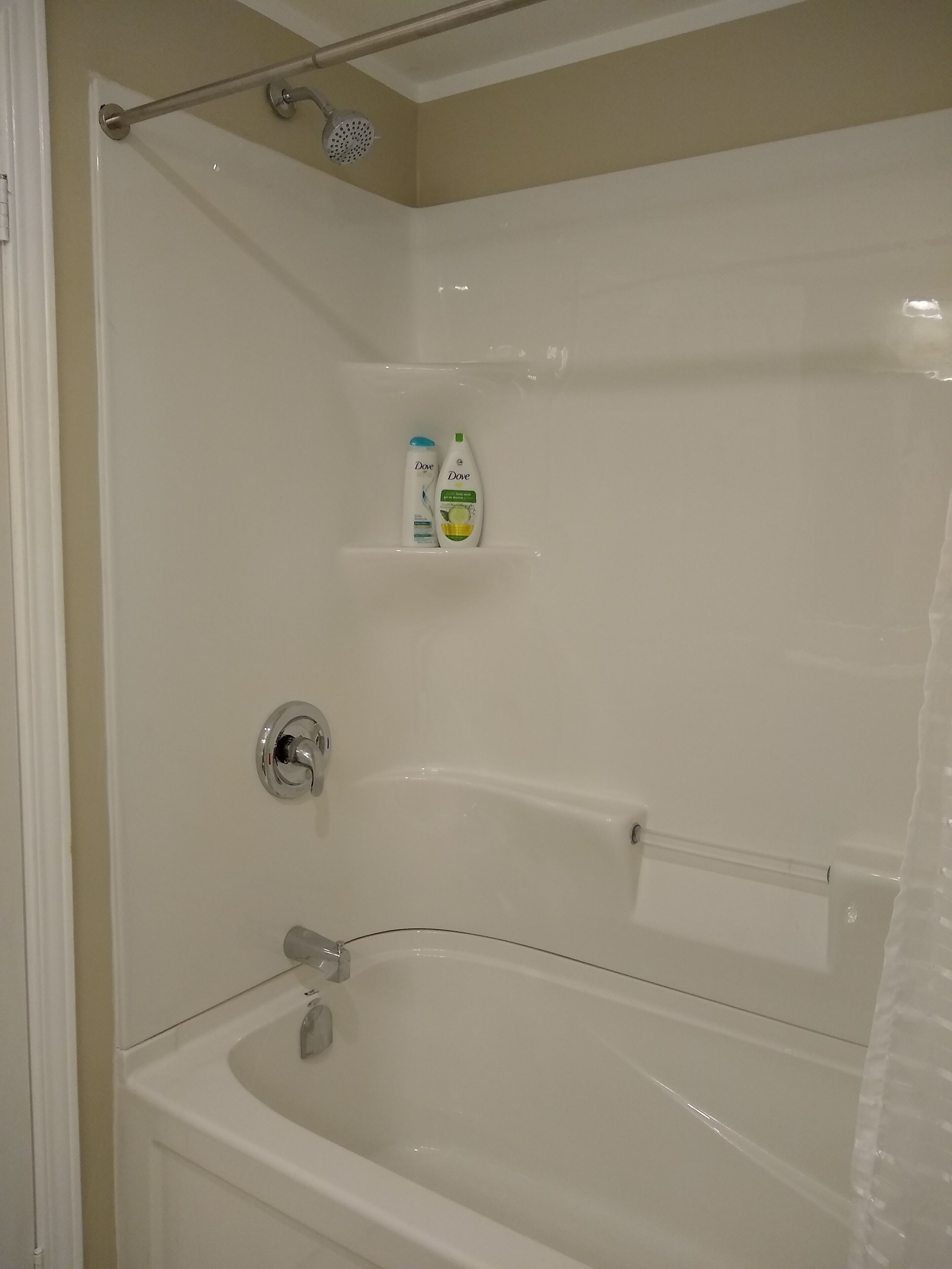 A bathroom with a bathtub, shower, and a shelf with toiletries.