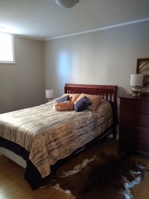 A bedroom with a bed, a dresser, a lamp, and a rug.