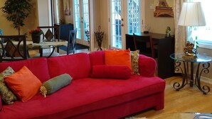 Ein Wohnzimmer mit einem roten Sofa, einem Glastisch und einem weißen, flauschigen Teppich.