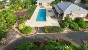 A residential property with a swimming pool, a covered patio, and a view of the ocean.