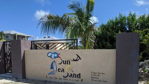 A sign with the text "Sun Sea Sand TCI.com" and "15 Lignum Vitae Drive, Long Bay Hills, Providenciales, Turks and Caicos Islands".