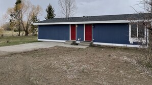 Un edificio a un piano con una porta rossa e una facciata blu.