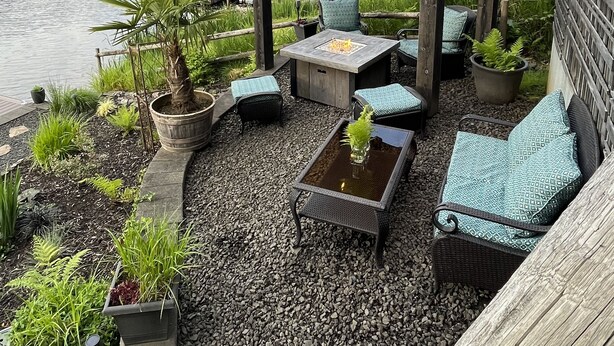 An outdoor patio with a pergola, seating, and a fire pit overlooking a lake. - Lakefront Cabin in Eatonville, WA (Eatonville)