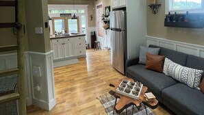 A spacious living area with a high ceiling, a wooden staircase, a kitchen with white cabinets, and a view of the outdoors. - Lakefront Cabin in Eatonville, WA (Eatonville)