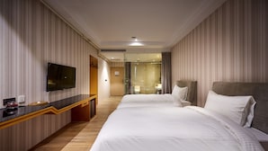 A hotel room with a large bed, a TV, a desk, and a shower area. - Oursea Hotel (Taichung)
