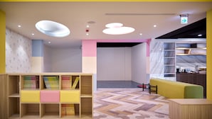 A modern, brightly colored interior with a wooden bookshelf, a seating area, and a marble backsplash. - Oursea Hotel (Taichung)