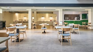 A spacious restaurant with wooden tables and chairs, a central kitchen area, and pendant lighting. - Oursea Hotel (Taichung)