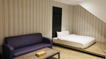 A modern bedroom with a purple sofa, a single bed, and a wooden coffee table.