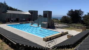 En swimmingpool med ett trädäck och utsikt över havet.
