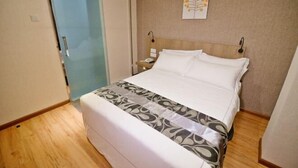 A hotel room with a bed, a bedside table with a lamp, a wall-mounted artwork, and a sliding door. - Diamond Inn (Kota Kinabalu)