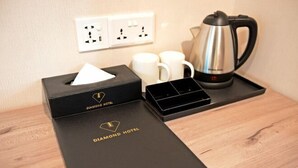 A hotel room with a neatly arranged table featuring a tissue box, a tray with a coffee pot, and two white mugs. - Diamond Inn (Kota Kinabalu)