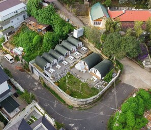 A hotel with multiple dome-shaped rooms, a fenced courtyard, and a road in the background. - HB Bungalow by Zuzu (Hanoi)
