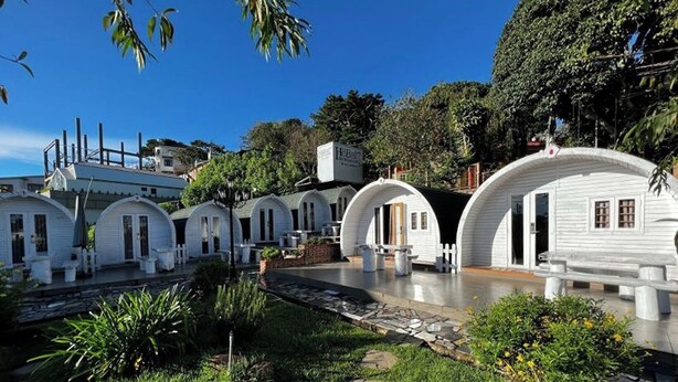 Una fila de cabañas blancas con forma de cúpula, con un sendero de piedra que las conduce, rodeadas de follaje y árboles.