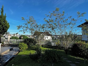 A residential area with a white fence, a paved driveway, and a variety of trees and shrubs. - HB Bungalow by Zuzu (Hanoi)