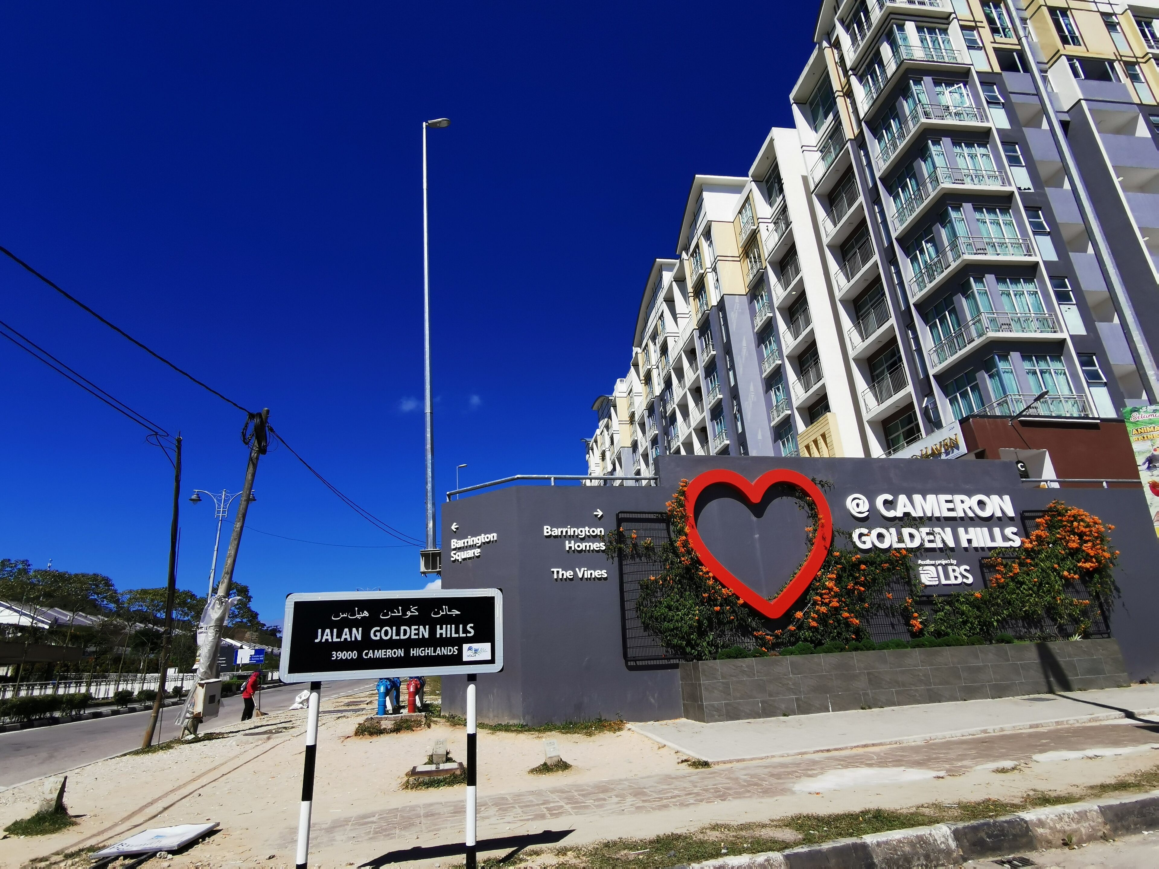 A sign for JALAN GOLDEN HILLS with a heart symbol and mentions Cameron Golden Hills.