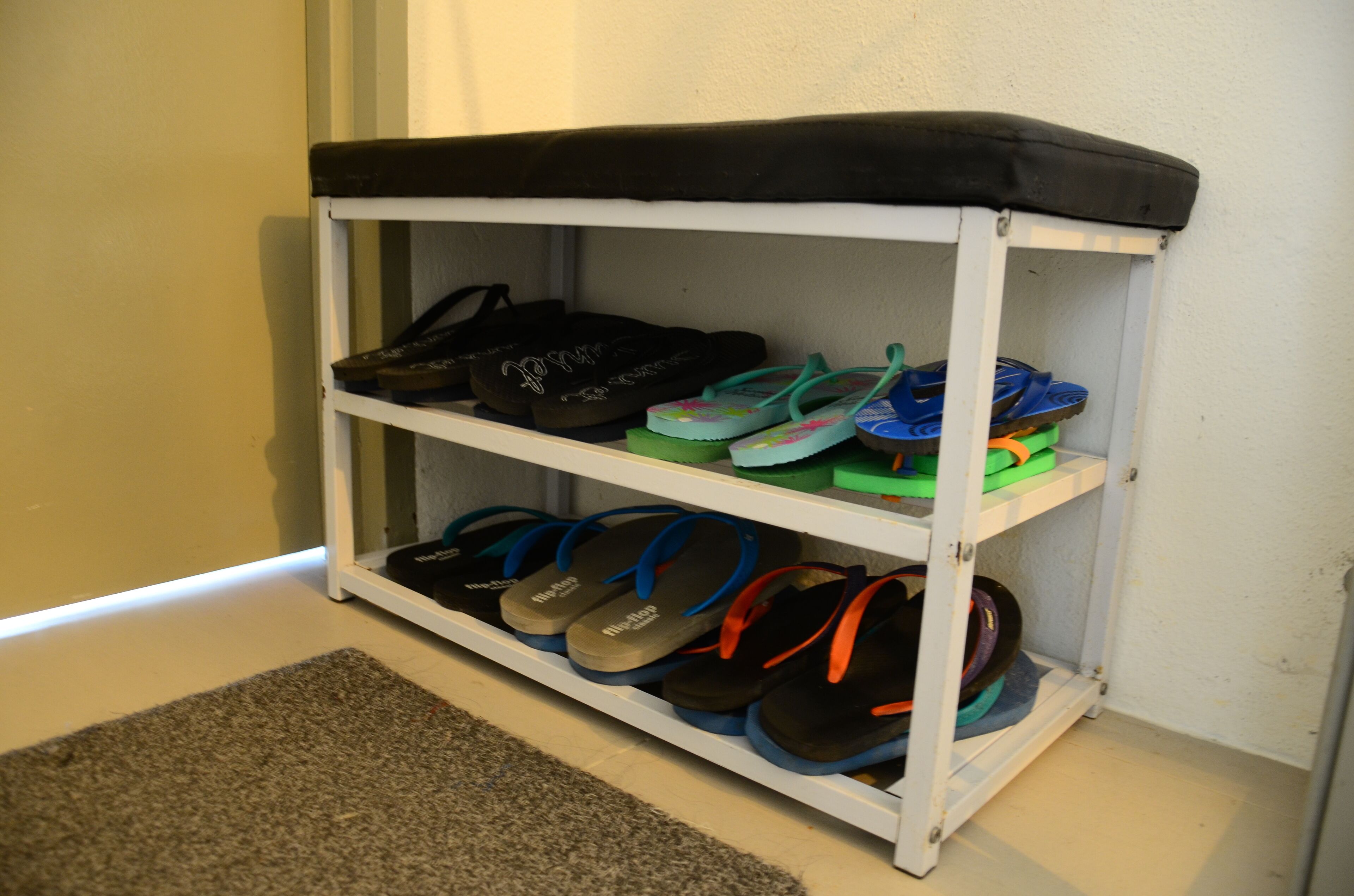 A shoe rack with multiple shelves holding various pairs of flip-flops.