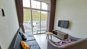 Ein modernes Wohnzimmer mit einer Couch, einem kleinen Tisch, einem Fernseher und Blick auf eine Wohngegend.