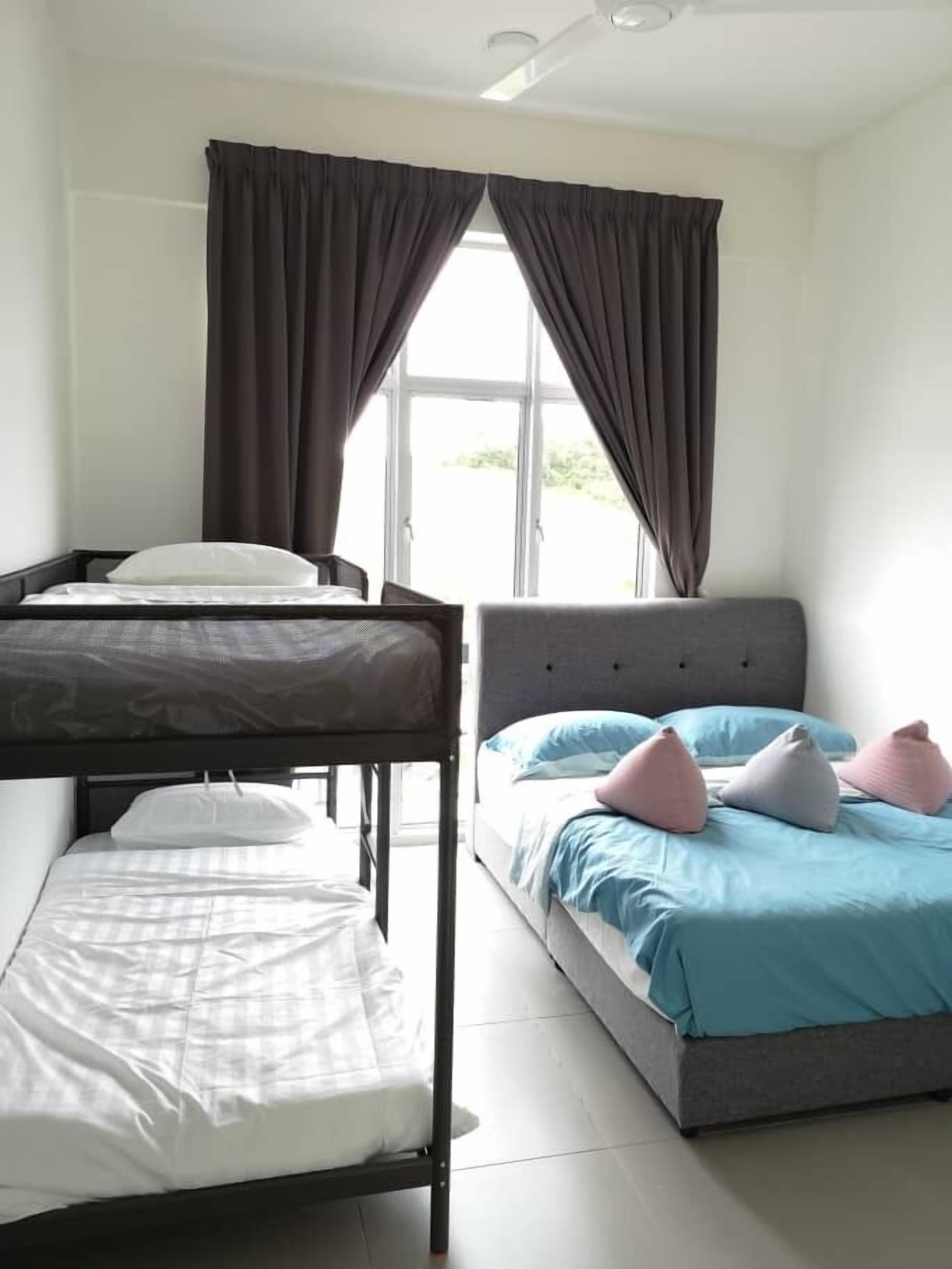 Een kamer met twee bedden, waarvan één een grijze hoofdbord heeft en de ander een witte. Er is een raam met gordijnen en de vloer is betegeld.