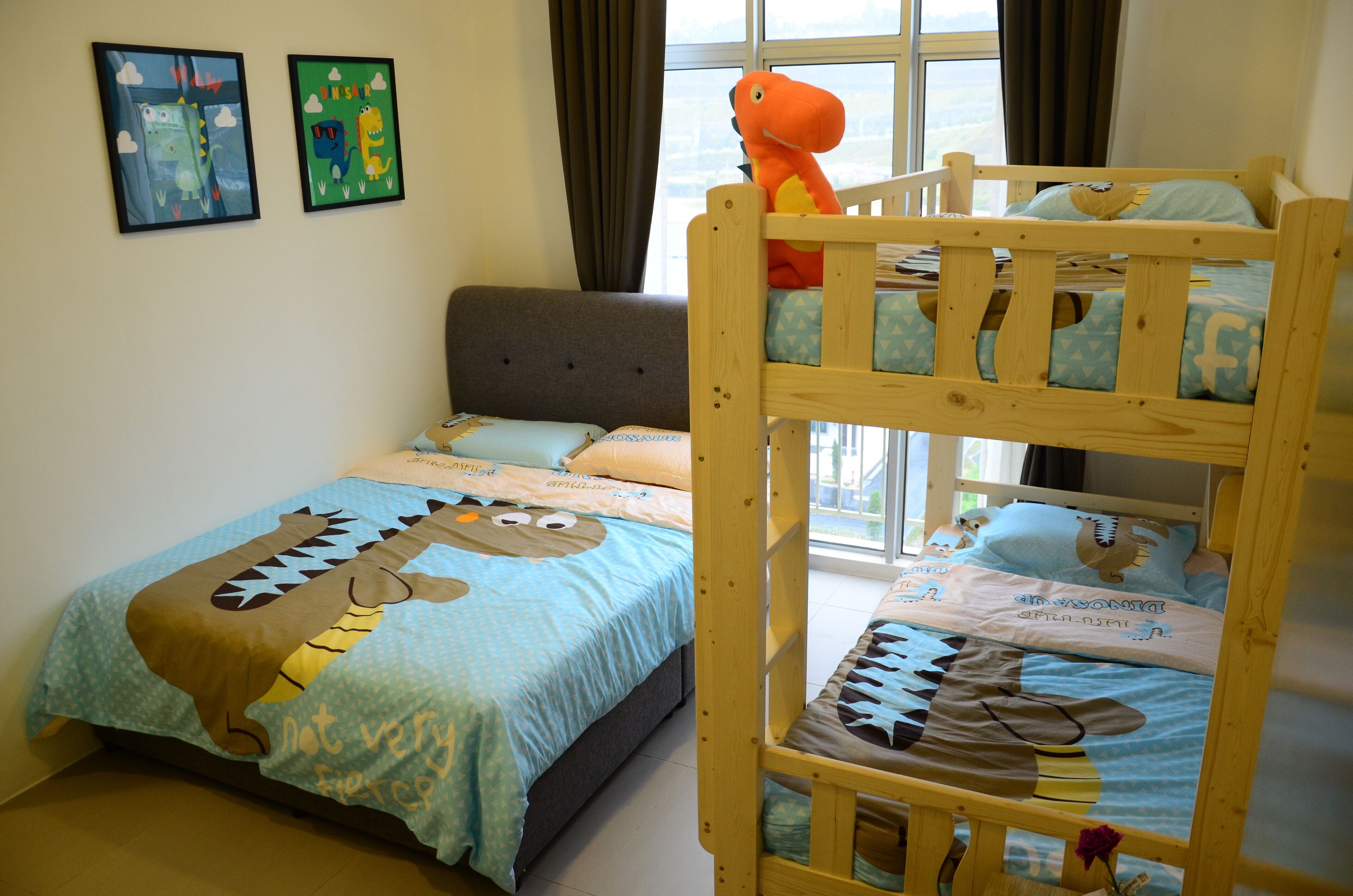 A child's bedroom with bunk beds, a grey sofa, and two framed pictures on the wall.