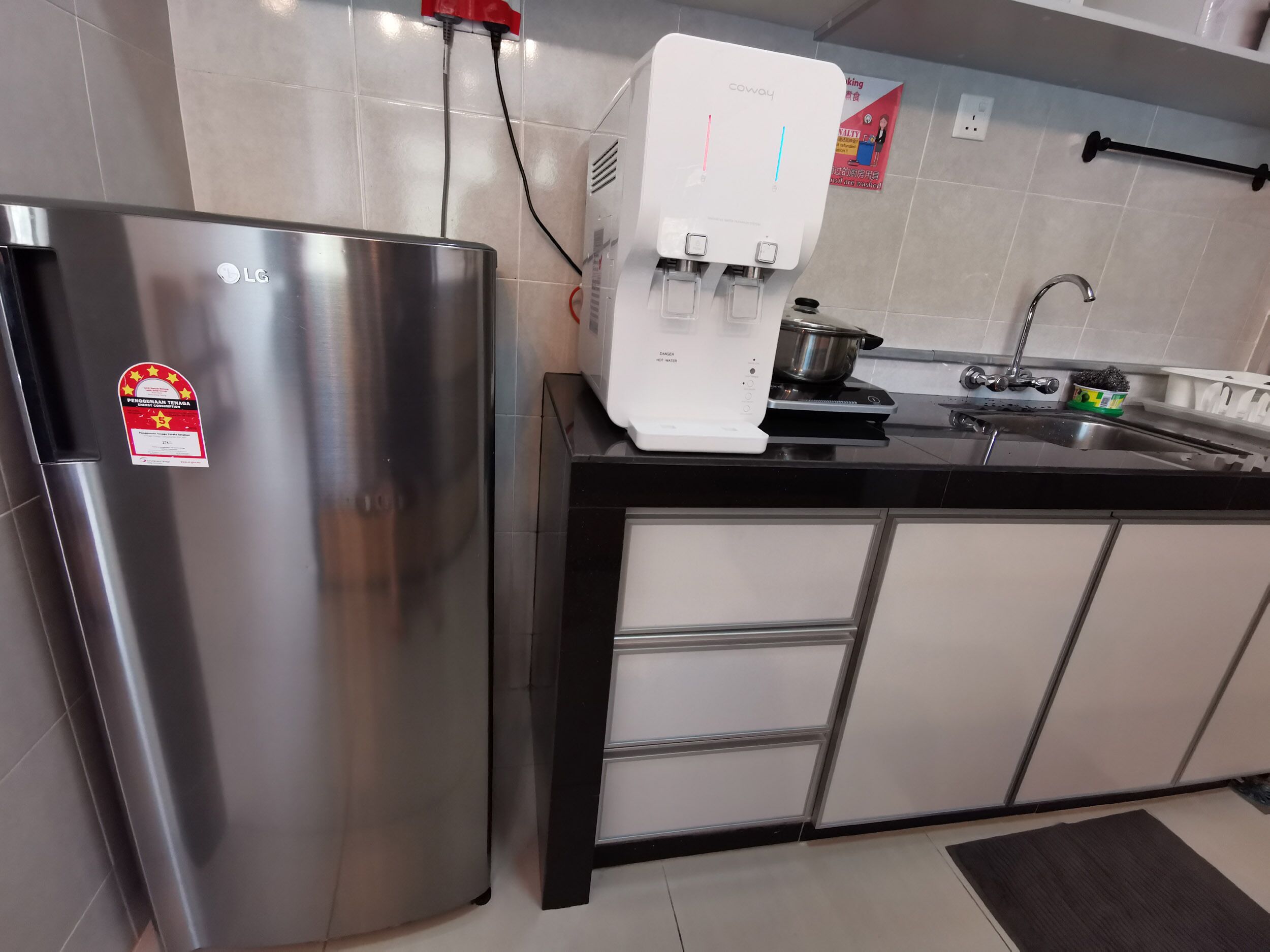 Una cocina moderna con un refrigerador de acero inoxidable, dispensador de agua, estufa y pileta.
