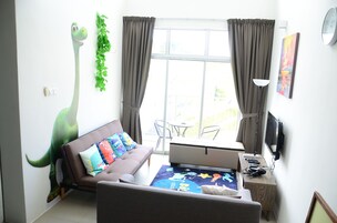A living room with a sofa, a coffee table, a TV, and a window with curtains.