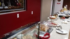 Montaje de bufé con un expositor de vidrio que contiene pasteles y una variedad de platos sobre una mesa larga.