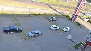 Un estacionamiento con varios autos, una camioneta negra y un auto blanco. Se ve un letrero con el texto "IMGRANTES".