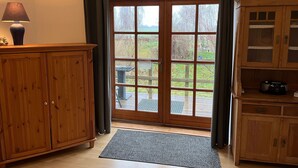 A room with a wooden cabinet, a table, and a view through a glass door to an outdoor area. - Apartment 1 with 2 bedrooms (4 adults + infant) on the ground floor - Villa Seeheim Ferienobjekt direkt (Boiensdorf)