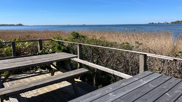 A wooden deck with benches overlooking a body of water and marshland. - Apartment 1 with 2 bedrooms (4 adults + infant) on the ground floor - Villa Seeheim Ferienobjekt direkt (Boiensdorf)