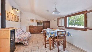 A dining area with a table set for four, a wooden cabinet, and a fireplace. - Cotoncello in a panoramic position (Marciana)