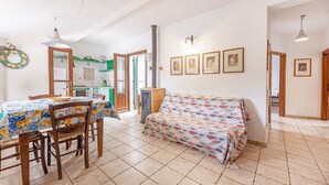 A dining area with a table and chairs, a sofa, and a kitchen in the background. - Cotoncello in a panoramic position (Marciana)