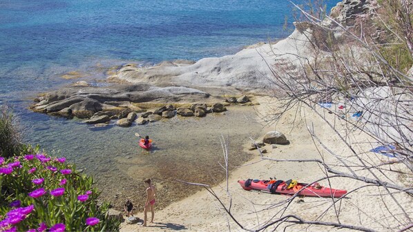 A rocky shoreline with clear water, a kayak, and a red canoe. - Cotoncello in a panoramic position (Marciana)