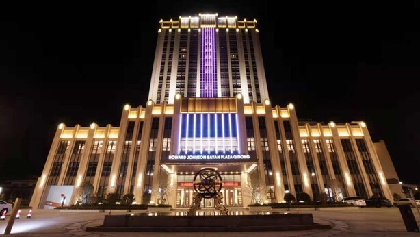 A large, modern building with a prominent entrance and a central illuminated sign.