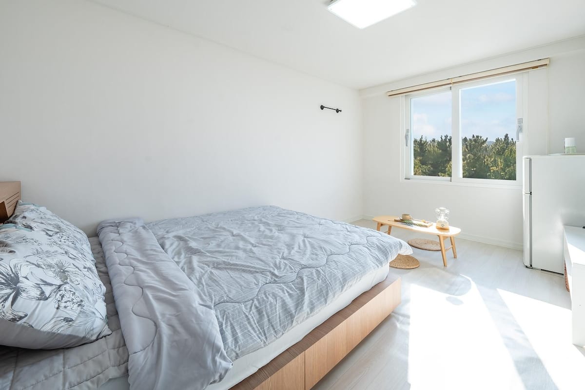 Een moderne slaapkamer met een bed, een klein tafeltje en een televisie.