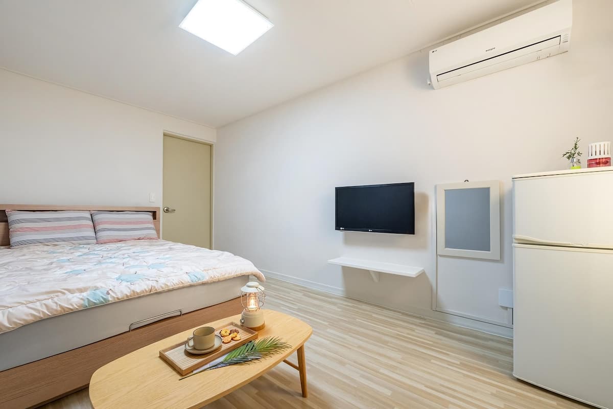 Een moderne slaapkamer met een bed, nachtkastje, televisie en koelkast.
