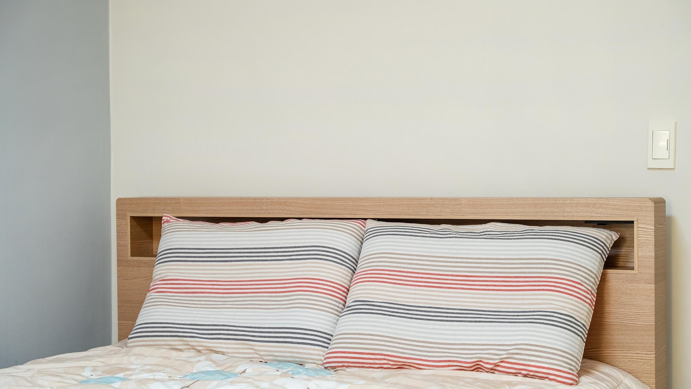 A bed with a wooden headboard and two striped pillows.