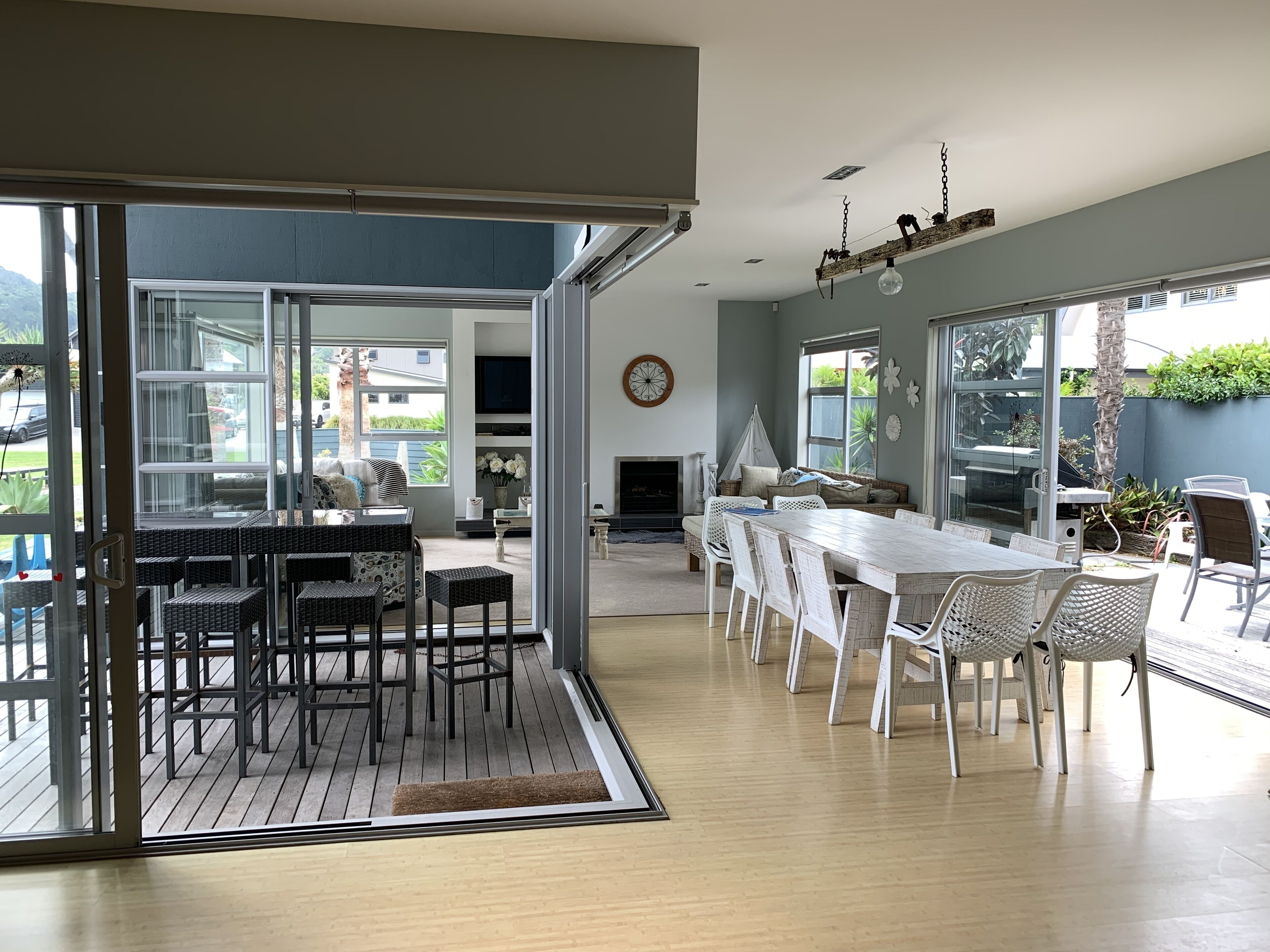 A spacious living area with a large dining table, multiple chairs, a fireplace, and a view of the outdoors.