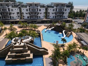 Ett semesterhotell med en central pool, palmer och utsikt över stranden.