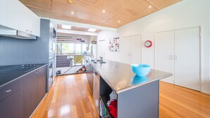 Een moderne keuken met een houten plafond, roestvrijstalen apparatuur en een blauwe kom op het aanrecht.