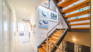 Een modern interieur met een trap, houten treden, metalen leuningen en kunstwerken aan de muren.