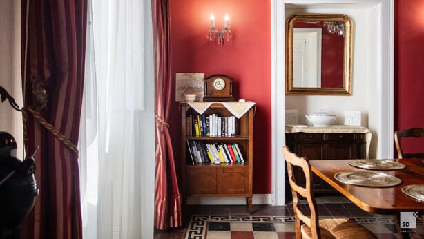 A dining area with a wooden table, chairs, a bookshelf, and a mirror on the wall. - Palazzo Toraldo di Francia (Tropea)