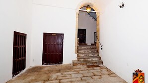 A staircase leading to an upper floor, a dark wooden door, and a white wall with a coat of arms. - Palazzo Toraldo di Francia (Tropea)