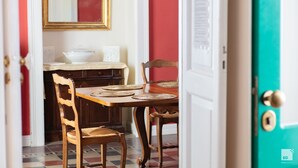 A dining area with a wooden table, chairs, and a white tablecloth. - Palazzo Toraldo di Francia (Tropea)