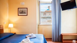A hotel room with a bed, a desk, a lamp, a TV, and a window with curtains. - Palazzo Toraldo di Francia (Tropea)