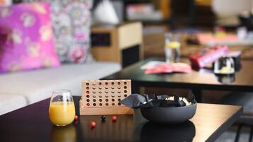 Ein modernes Wohnzimmer mit Couchtisch, einem Orangensaftglas, einem Holzpuzzle und einer Schüssel mit Snacks.