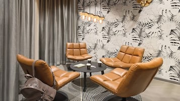 A modern lounge area with leather chairs, a round table, and a patterned wall.