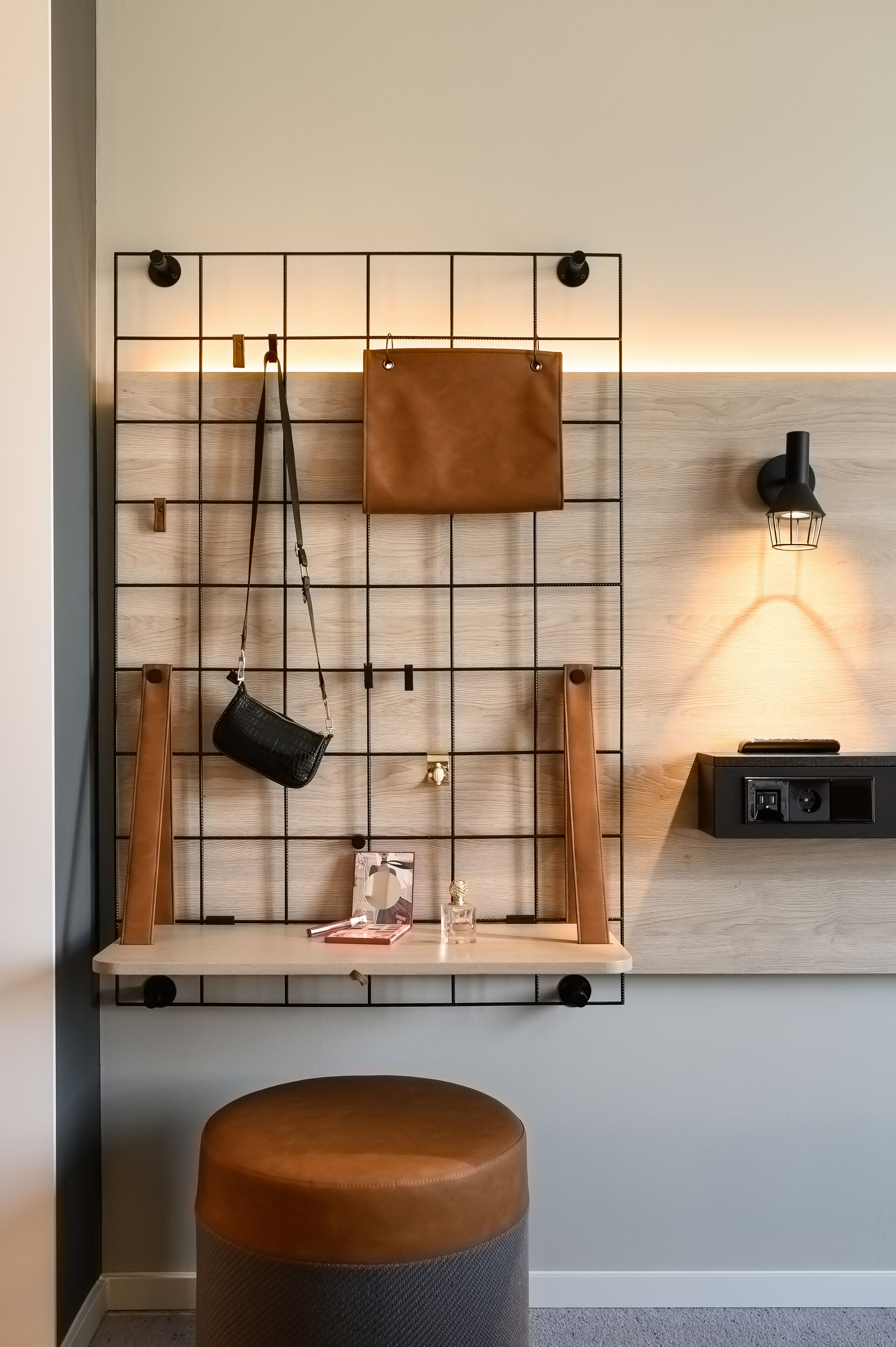 A wall-mounted shelf with leather bags and a small table with a lamp.