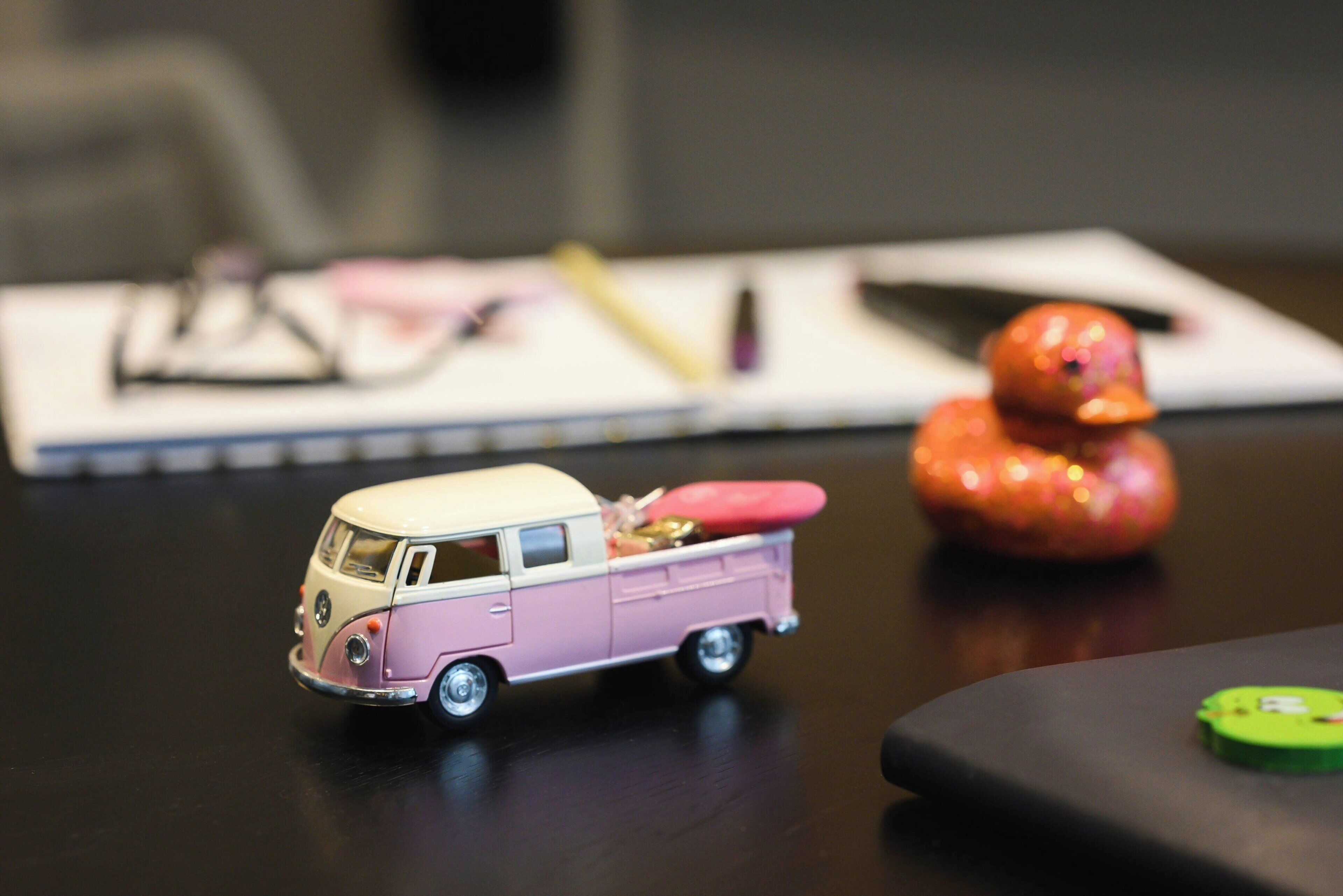 A toy van and a rubber duck on a table.